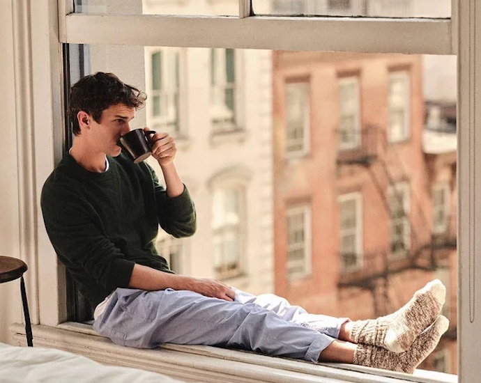 man drinking coffee on window ledge