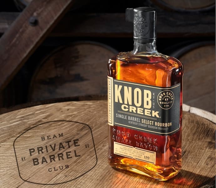 aa bottle of knob creek bourbon sitting on a barrel